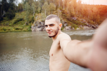 Selfy. A man takes a picture of himself against the background of a mountain river in the rocks