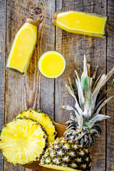 Freshly squeezed pineapple juice near fruit slices on wooden background top view