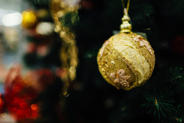 Close-Up of golden bauble hanging from a decorated Christmas tree. Christmas ornament