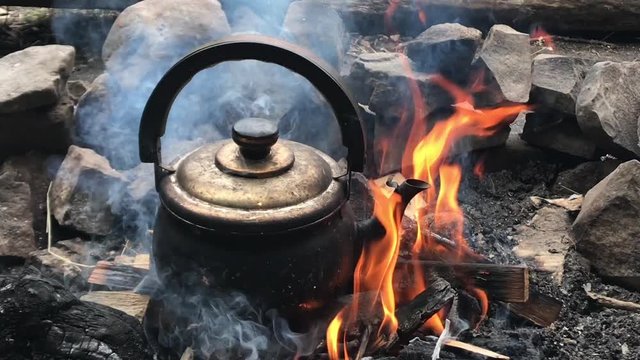 Boiling Kettle smoke flying ashes fire arms kettle fire log steam Camping Burning hiking camp woods nature wood trip authentic summer kitchen backpack axe tea pot boiling over open fire