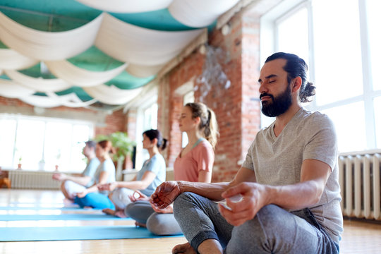 man with group of people meditating at yoga studio