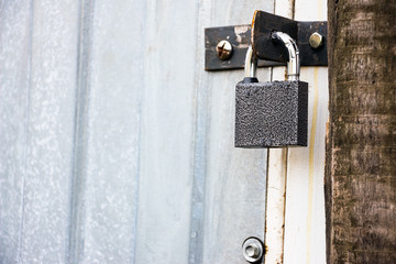 Small closed padlock hanging on the hinges