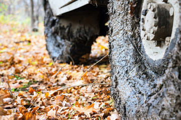 Dirty the wheels of the car after off-road. The car is in the autumn forest, fallen leaves. Selective focus