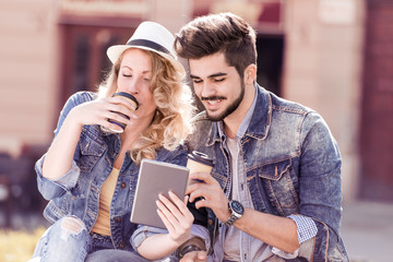 Couple using tablet and drink coffee to go.