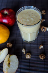 Fresh autumn raw smoothie with apples, oranges, banana and walnuts on the dark background