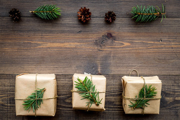Gifts for new year wrapped in craft paper near spruce branches and cones on wooden background top view pattern copyspace