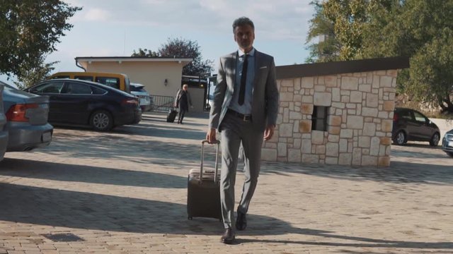 Mature businessman with suitcase in a car park.