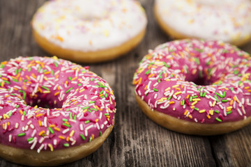 Multicolored donuts  on a wooden background.