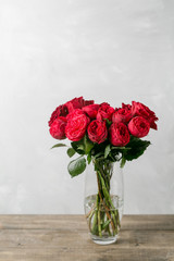 Red roses in vase on wooden table. garden peony Red Piano