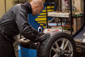 auto mechanic balancing car wheel at workshop