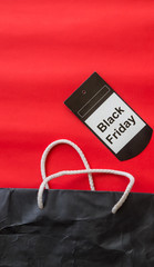 Bสack shopping bag on red background with Black Friday tag, view from above