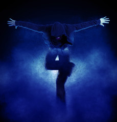 Fototapeta premium Young man break dancing on dark smoke background