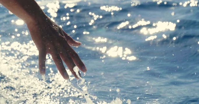 A girl touches a wave hand, a background of blue sea water