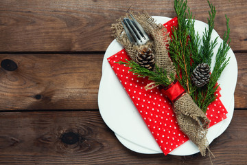 Christmas table setting with fork and knife in sackcloth and spruce branches cones and Christmas decorations on a wooden background with copy space top view flat, holiday concept