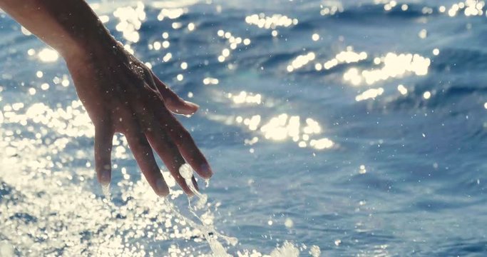A girl touches a wave hand, a background of blue sea water
