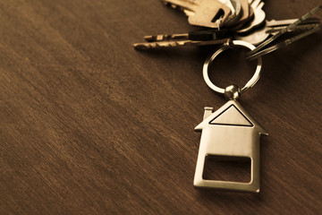 Bunch of keys with house shaped keychain on white wood