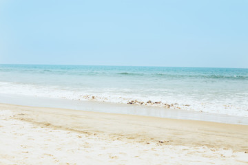 Fototapeta na wymiar Tropical sandy beach, view of the sea with waves and sunny sky.
