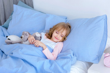 child, little girl sleeping in bed with toy rabbit	