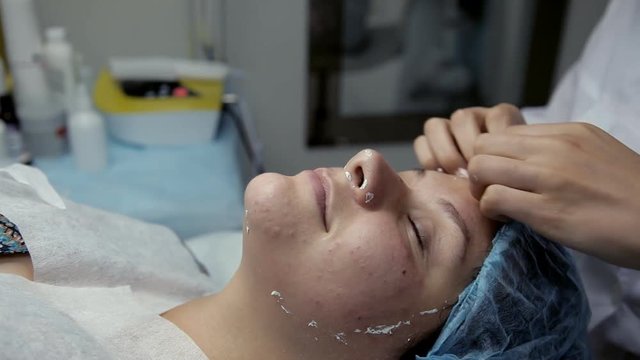 Beauty salon beautician removes the remains of alginate mask from the face of the client