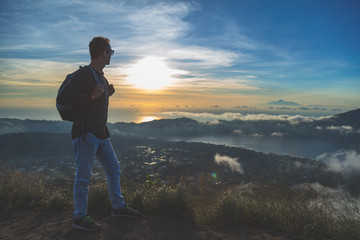 Man hiker looking to distant landscape from Mt. Batur, Bali, Indonesia.