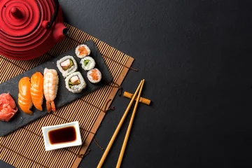 Muurstickers Set sushi met wasabi, sojasaus en theepot op zwarte stenen achtergrond. Bovenaanzicht © Leszek Czerwonka