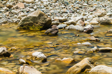 Long exposure photo of the river flowing in rocky ravine in sunny day