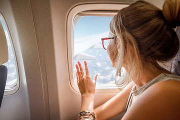 Obraz premium Młoda kobieta cieszy się widok przez okno samolotu obsiadanie podczas lota w samolocie