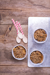 Ceramic ramekins with apple crumble  on a baking dish. Wooden background. 