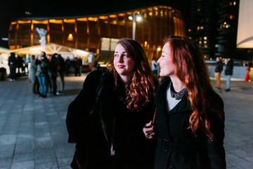 two young women friends walking outdoor night having fun - happiness, girl power, interaction concept