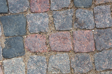 cobblestone pavement. Texture of cobblestone road close-up. Part of the road paved with red  black granite.