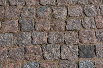 cobblestone pavement. Texture of cobblestone road close-up. Part of the road paved with red  black granite.