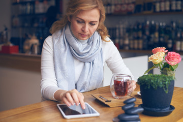 Thoughtful mature woman using tablet with black screen