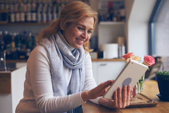 Smiley Mature Woman Using Digital Tablet In Cafe