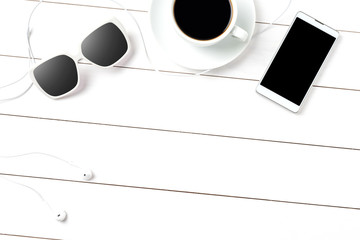 Coffee cup, sunglasses and smart phone on white wooden background