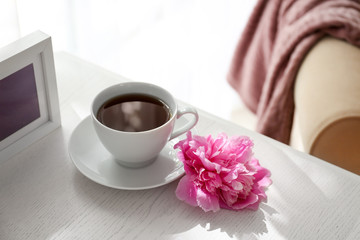 Cup of coffee and peony flower on table