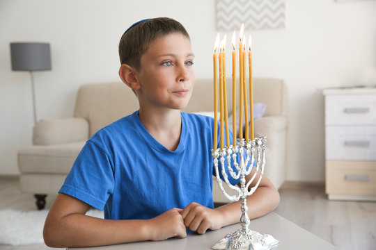 Jewish boy looking at flame of candles in menorah, indoors
