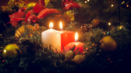 Winter holidays background. Christmas candles burning on advent wreath next to colorful gift boxes