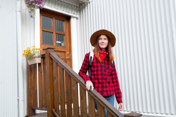 Portrait of a young girl with a smile in a red checkered shirt on a wooden house close-up background.