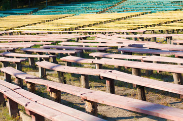 Many old colored benches outdoors on sunny day