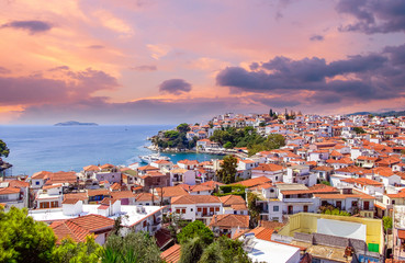 Naklejka na ściany i meble Sunset over Skiathos town on Skiatos Island, Greece. Beautiful view of the old town with boats in the harbour.