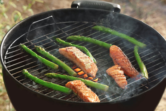 Tasty salmon slices with vegetables on barbecue grill outdoors