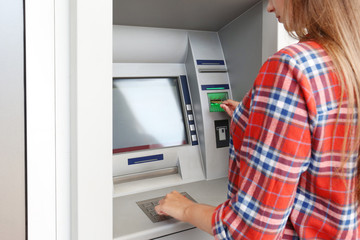 Woman inserting credit card into cash machine