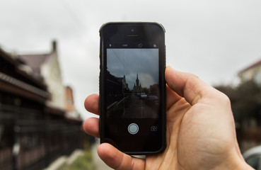 In the hand of the phone, on the screen is the landscape of a beautiful old building