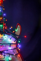 Merry christmas guitar wrapped by colorful garland as a gift background