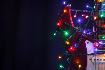 Merry christmas guitar wrapped by colorful garland as a gift background