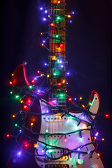 Merry christmas guitar wrapped by colorful garland as a gift background