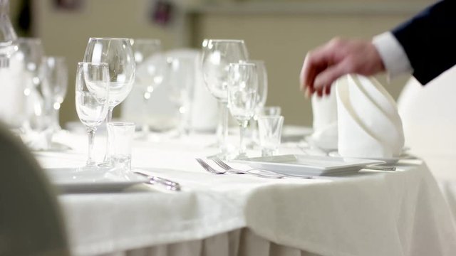 Waiter hand moving the cutlery on the banquet table at restaurant