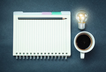 Light bulb with coffee and notepad on a blue background.