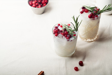 Perfect christmas cocktail: coconut margarita with cranberries and rosemary. Minimalistic concept. Linen cloth and white background. Horizontal composition with copy space.