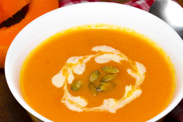 Pumpkin and carrot soup with cream and parsley on dark wooden background Top view